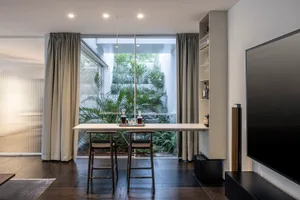A modern living room featuring a high-end interior design with wooden floors, glass walls, and a mix of materials.