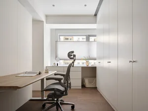 A modern minimalist home office featuring a wooden desk, glass window, and ergonomic chair.