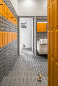 A modern corridor with concrete flooring and metal cabinets leading to a bathroom