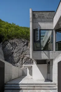 Modern minimalist house exterior with concrete walls and large windows.