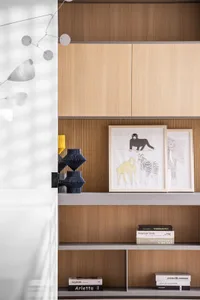A minimalist interior design showcases shelves made of wood with framed illustrations and books.