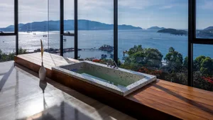 Modern bathroom featuring a concrete bathtub with a stunning view of the ocean.