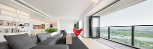Modern minimalist living room with a grey sofa, red chair, and wooden floor.