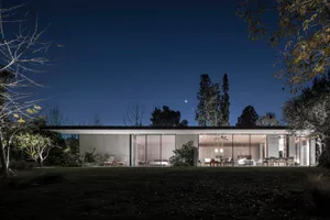 Modern residential exterior illuminated at night with a focus on concrete and glass surfaces.