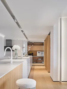 Modern residential kitchen featuring wooden cabinets and white countertops with a white vase and white floral arrangement on 