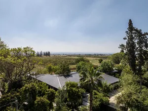A modern residential property with a metallic roofing system surrounded by lush greenery.