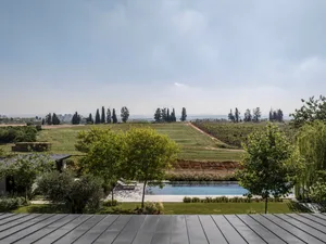 A serene pool surrounded by greenery with a beautiful view of the countryside and cityscape in the distance.