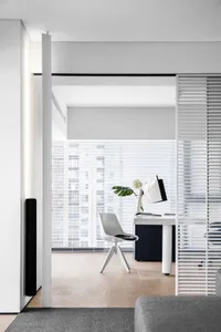 A modern minimalist workstation featuring a white ergonomic chair in a contemporary interior.