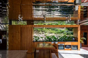 Modern residential kitchen featuring a wooden dining table and chairs, an open-plan layout, and a view of the outdoors with a