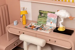 A modern casual home office with pink furniture and decorative elements.