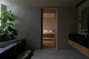 A minimalist bedroom with grey walls, wooden floor, and bed.