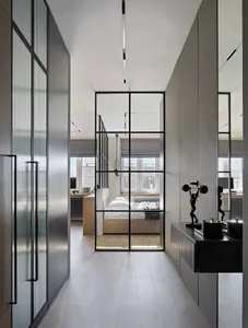 A modern apartment bedroom featuring a glass partition and wooden floors with natural light streaming in from the windows.