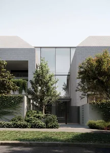 A modern brick house with large glass windows and a gated entrance.