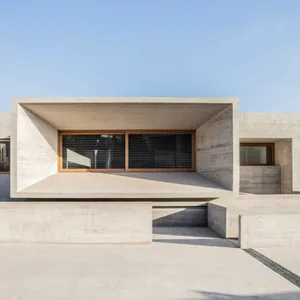 Modern building exterior featuring concrete walls and large windows on a bright day.