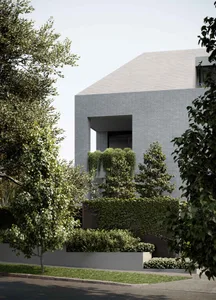 Modern house with brick exterior, large windows, and greenery.