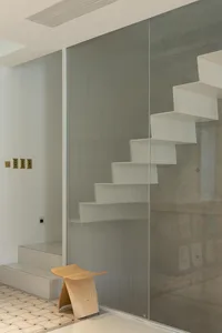 Modern interior design featuring a minimalist white staircase enclosed with frosted glass walls.