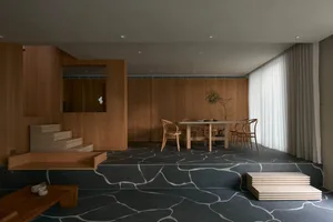 A modern living room with dark wood flooring, wooden furniture, and a minimalistic design.