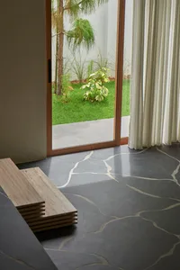 Luxurious modern living room with concrete flooring and a view of a well-maintained garden with greenery and grass.