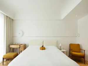 Minimalist bedroom with a yellow pumpkin on the bed.
