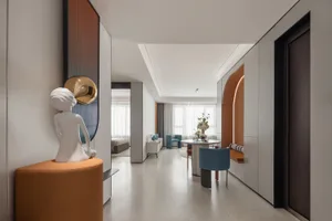 A modern minimalist living space featuring white walls and a dining area with a round table and blue chairs.