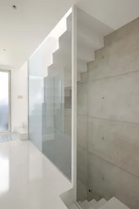 Minimalist interior design featuring a modern staircase with concrete and glass elements