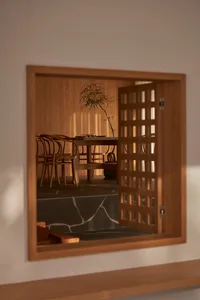 A view of a restaurant interior through a wooden sliding door with a lattice design, featuring a wooden dining table, chairs,