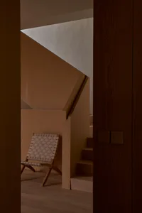 Industrial-style interior with wooden stairs and a woven leather chair.