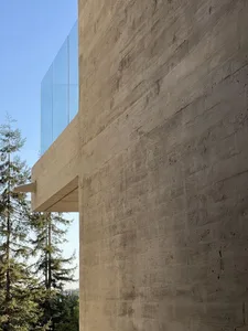 A modern building with a textured concrete exterior and a glass balcony.