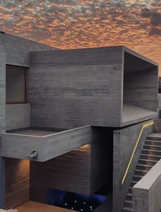 A modern, concrete exterior building with a sunset sky in the background.