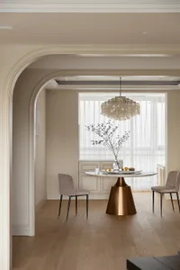 A minimalist dining room featuring a modern table, chairs, and chandelier.