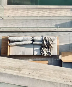 Modern outdoor sectional sofa with concrete frame and white cushions.