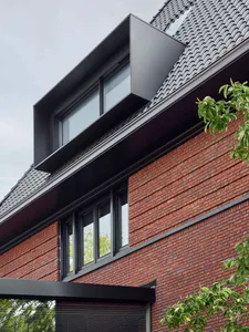 Modern house with black brick exterior and large windows.