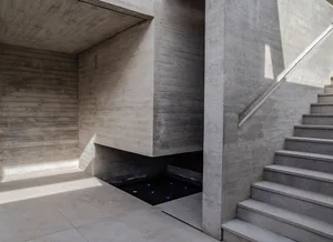 Modern staircase with concrete walls and steps, illuminated by sunlight.