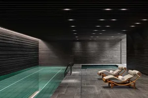 Modern indoor swimming pool with concrete walls, tiled bottom, and concrete deck.