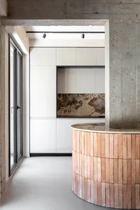 A modern kitchen with white cabinets, a stone countertop, and a circular brick column.