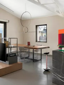 Modern interior design featuring a wooden dining table with metal chairs and a minimalist metal light fixture hanging above.