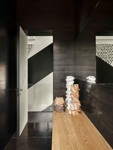 A modern entrance hall features black wood walls and a wooden bench with concrete sculptures.