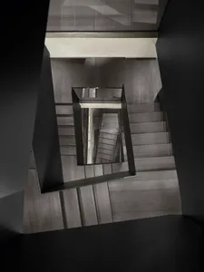 A modern interior featuring a wooden staircase with glass railings.