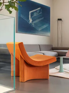 A modern, orange lounge chair in a minimalist living room setting.