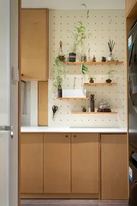 An industrial minimalist kitchen storage area with wooden cabinets, pegboard shelves, and potted plants.