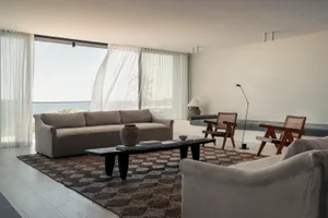 A modern minimalist living room featuring beige and gray fabric furniture and a patterned area rug.
