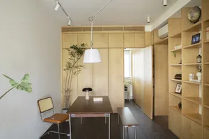 A minimalist living room featuring wooden furniture and light-colored walls.