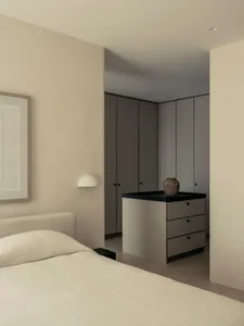 Minimalist bedroom with neutral-colored cabinets and a bed.