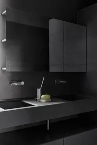A modern bathroom with a black concrete countertop and double sinks, featuring a minimalist design with sleek silver faucets 