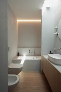 Minimalist bathroom featuring a concrete bathtub and sink with a wooden vanity