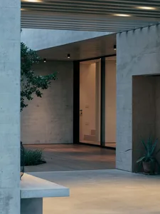 A modern concrete entryway with indoor plants and lighting.