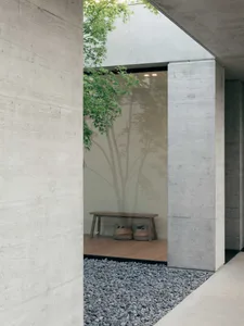 A minimalistic entryway with concrete walls and a wooden bench.