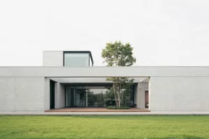 Modern house exterior featuring cement walls and a glass window.