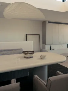 A minimalist dining room featuring a concrete table, chairs, and bowl with another bowl nearby.