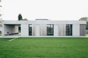 A contemporary minimalist house with concrete, metal, and wooden exterior materials.